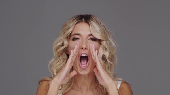 Studio portrait of young and beautiful blond woman over grey background.