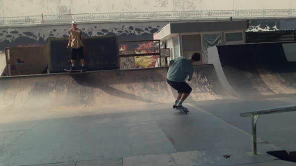 Teenagers Friends Practicing Together on Scooter and Skate Board at Skatepark