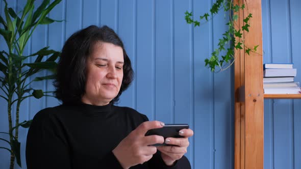 Middle Aged Old Woman Play Mobile Games on Mobile Phone at Home