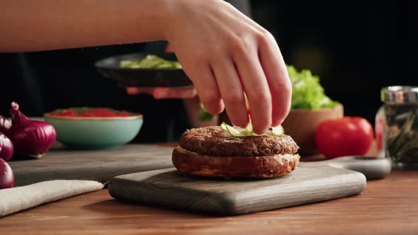 Chef Cooking Burger Putting Sliced Cucumber on Meat Making Sandwich Fast Food Concept Recipe of