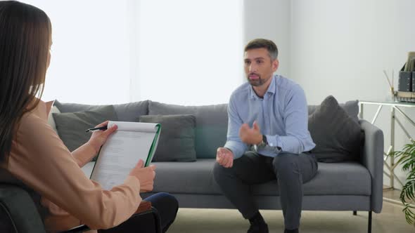 Unfocused Emotional Man Patient with Mental Health Problems Talking to Therapist