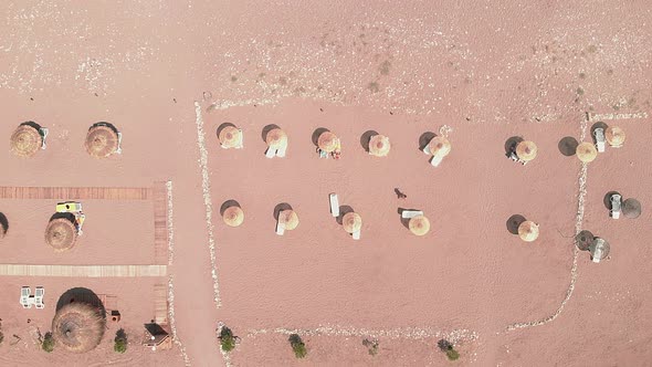 Umbrellas and sunbeds on sandy beach, top view.