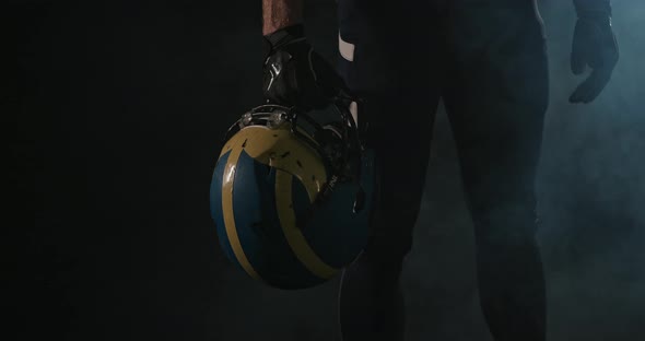 American Football Sportsman Player Holding a Helmet in His Hand on Black Background