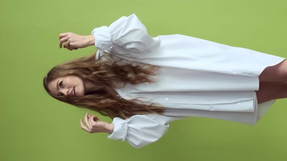 Girl With Long Hair Dancing On Background Of Light Green Wall