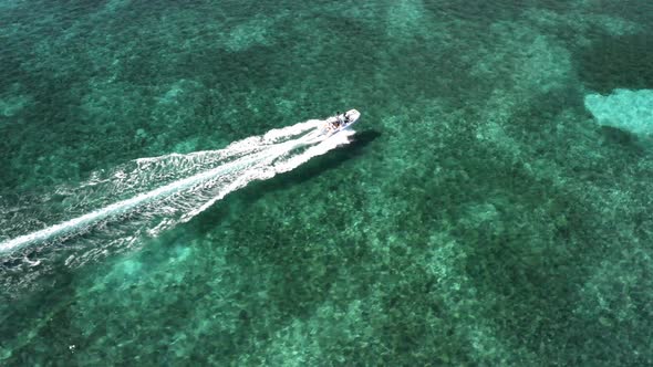 Speedboat Leaving Wake On Surface Of Clear Blue Water Of Ocean Near The Bahamas. - aerial