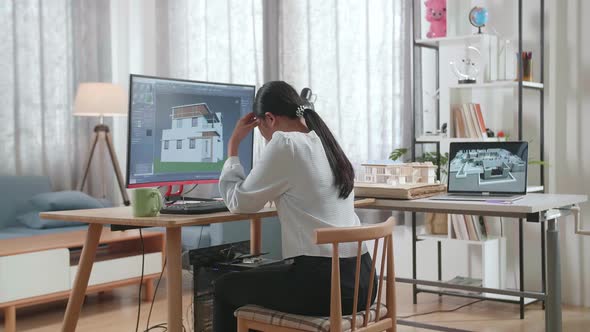 Asian Woman Engineer Having A Headache While Designing House On A Desktop At Home