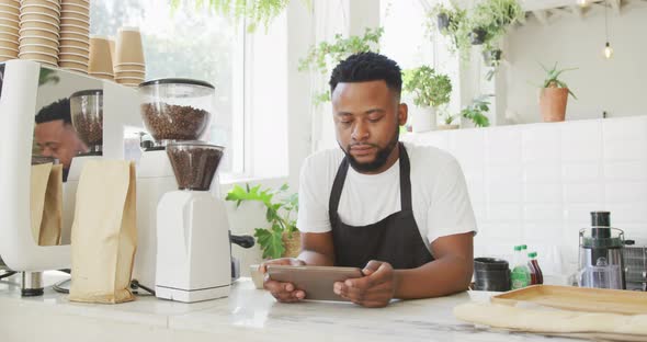 African american male cafe owner standing by counter using tablet at cafe