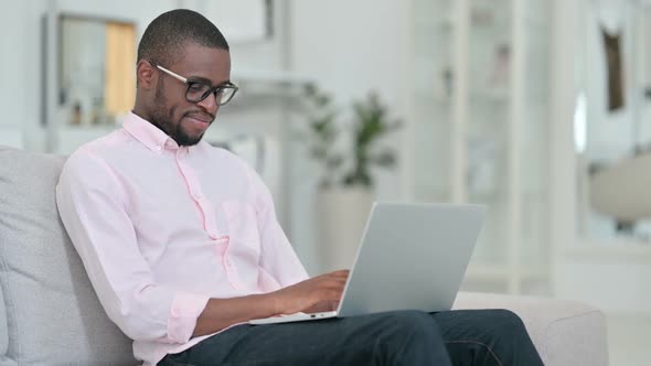 African Man with Laptop Smiling at the Camera at Home