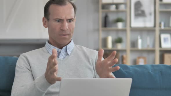 Frustrated Aged Man Reacting to Loss on Laptop While Sitting on Couch