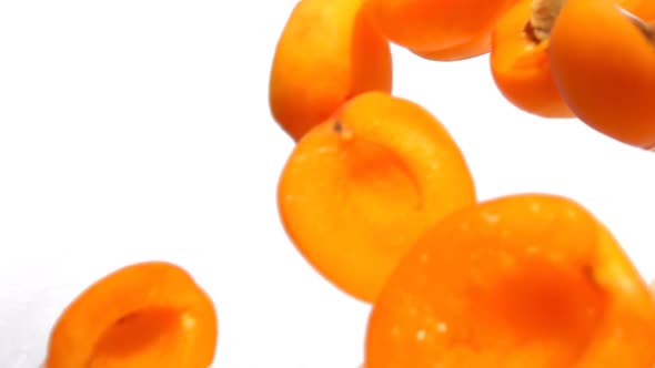 Halves of Freshly Cut Apricot Fly and Bounce on a White Background