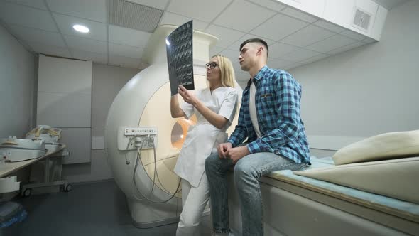 Woman doctor explains the results of MRI scanning for young male patient