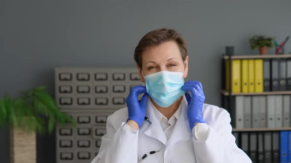 Senior Female Doctor Puts on a Protective Blue Mask
