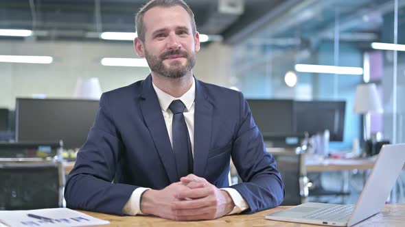 Cheerful Young Businessman Giving Documents in Office