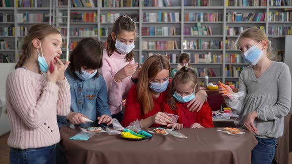 Masked Girls Decorating Cookies During Masterclass