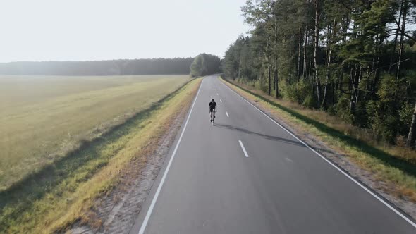 Aerial Video of Cyclist Riding a Road Bike on a Highway Near Field in Summer