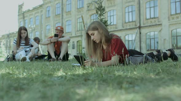 Thougthful Student with Tablet Pc Studying on Lawn