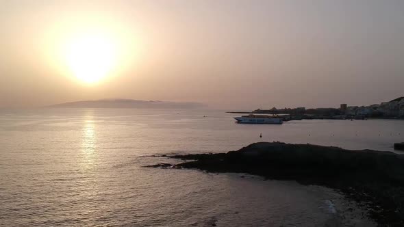 A drone tilt-down shot of a transport boat leaving port at Costa De Las Americas with birds flying.