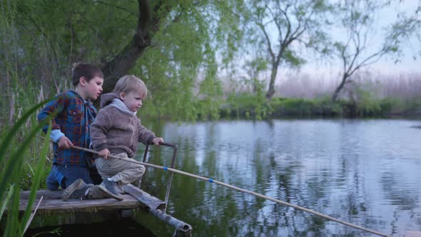 Relationship, Friendly Boy Brothers Catch Fish on a Wooden Fishing Rod Sitting on the Boards 