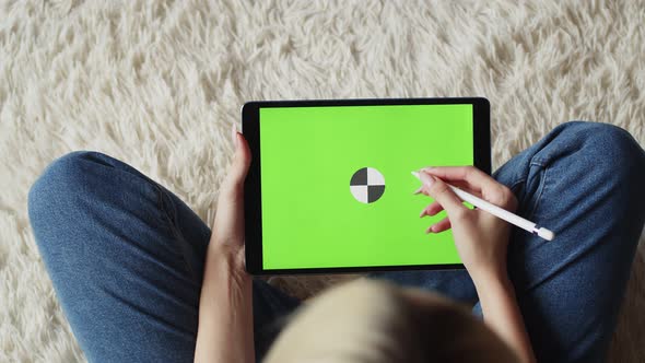 Woman Sits in Lotus Position and Draws with Stylus on Electronic Tablet with Chromakey Green Screen