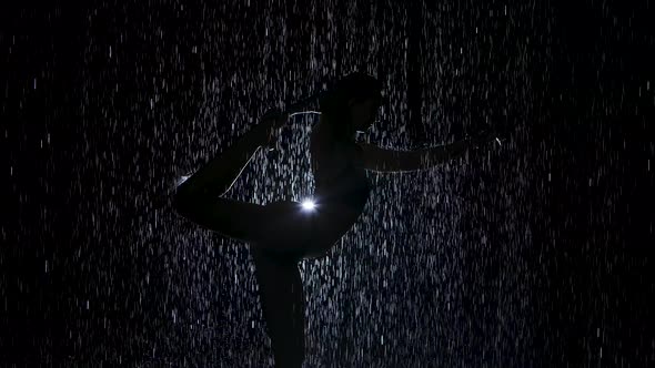 Dancer Pose in the Pouring Rain. Wet Body Silhouette of Young Woman Practicing Yoga Exercises in