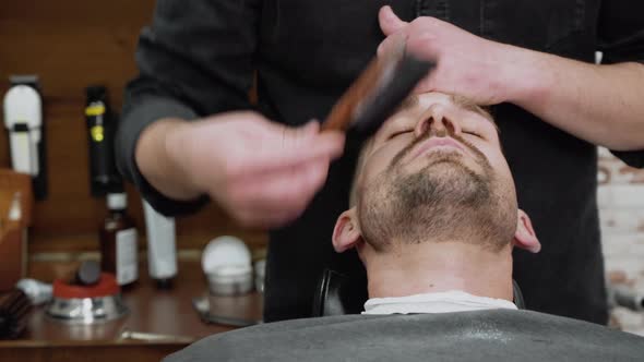 Shot of a Barber Using a Brush on His Client's Beard