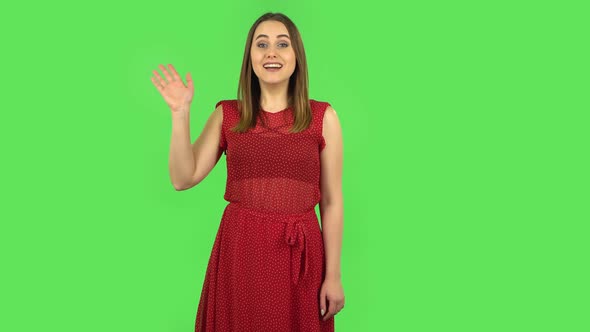 Tender Girl in Red Dress Is Waving Hand and Showing Gesture Come Here. Green Screen