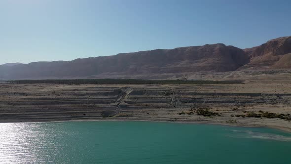 Aerial side slide shot over green water in Israel Dead sea, Sunny day