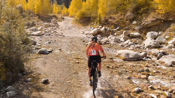 Man Is Crossing the River By Bicycle in the Mountains Shot By Drone