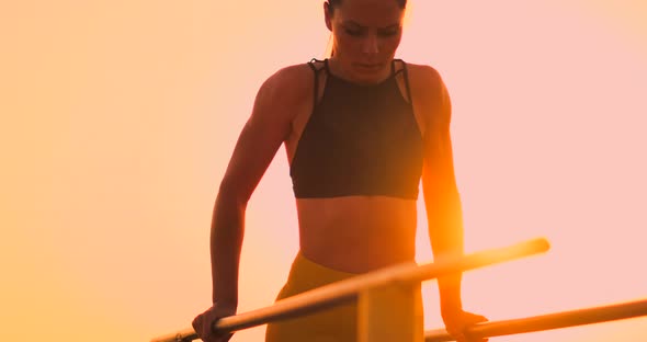 A Beautiful Woman at Dawn Performs pushUPS on Parallel Bars in Slow Motion