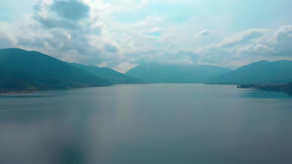 Descending aerial shot of the Tegernsee on a cloudy spring day.