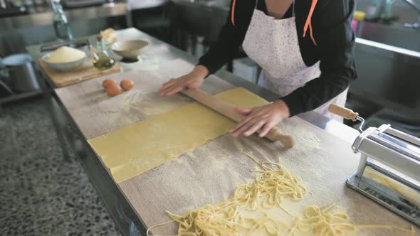Close up female hands roll the dough preparing fresh homemade pasta