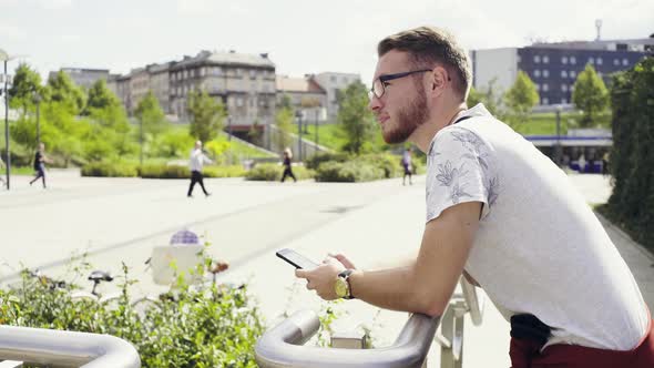 Young Man Using Mobile Phone at City Square