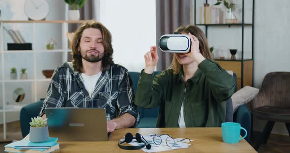 Guy Working on Computer while His Excited Joyful Girlfriend in Special 3d Glasses Watching Vision
