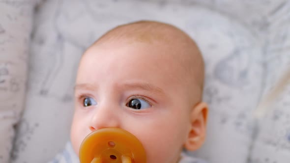 Hand of mother caressing her cute baby lying in the crib with pacifier at home 4k