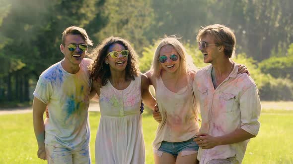 Group of Friends Covered in Colored Paint Dancing, Cheering at Outdoor Party