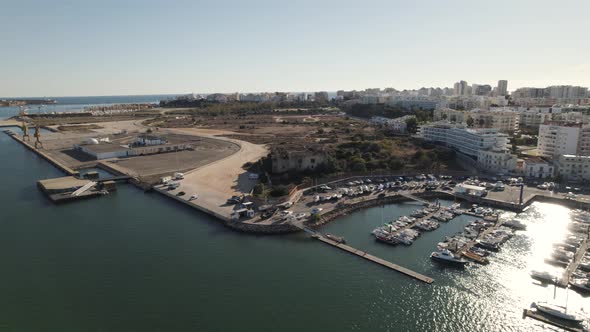 Yacht docked at Portimao port. Portimao cityscape bathed by sunbeam. Aerial view