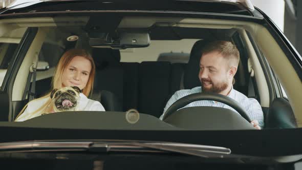 Young Couple with a Dog in a Car Dealership