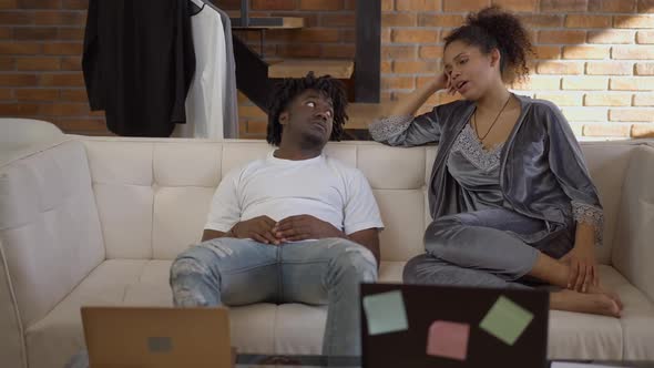 Wide Shot Portrait of Young African American Man and Woman Sitting on Comfortable Couch Talking on