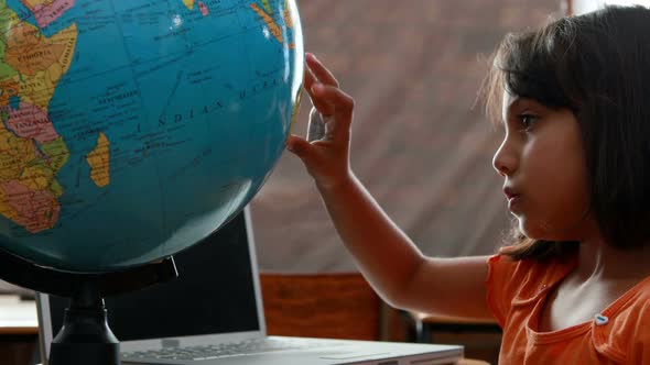 Little girl looking at globe in classroom