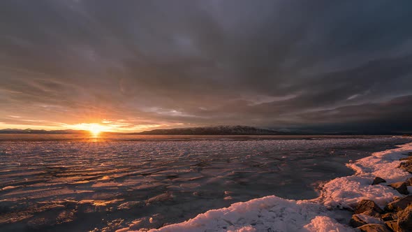 Sun setting over frozen lake as sky lights up with vibrant colors