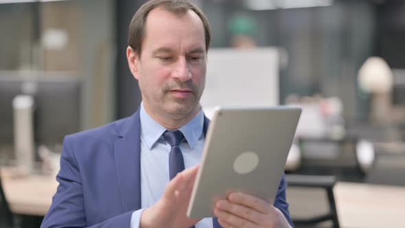 Portrait of Attractive Businessman Using Tablet in Office