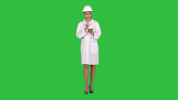 Woman engineer writing checklist walking on a Green Screen