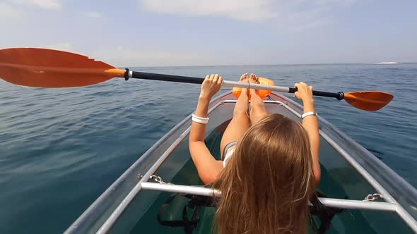 Young Attractive Brunette Woman with Long Hair in White Swimsuit Swimming on Transparent Kayak