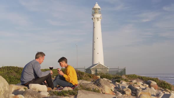 Couple drinking wine by the sea near a lighthouse