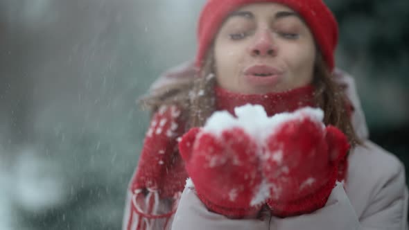 Slow Motion Playful Laughing Woman Blows Snow From Mittens in Winter Park After Snowfall at Frosty