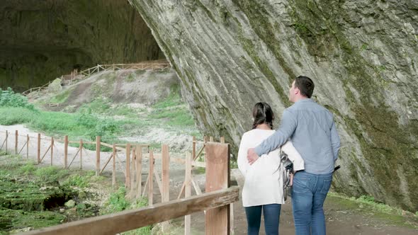 Couple Looking at a Cave in the Mountains