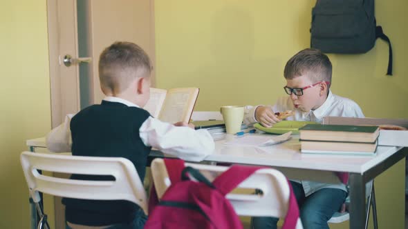 Happy Boy Eats Pizza with Friend Reading Book at Table