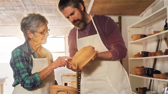 Male and female potter interacting while examining a pot