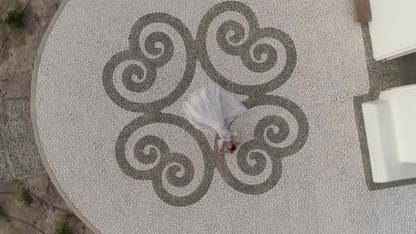 Aerial view of woman with wedding dress lay down, Santorini island, Greece.