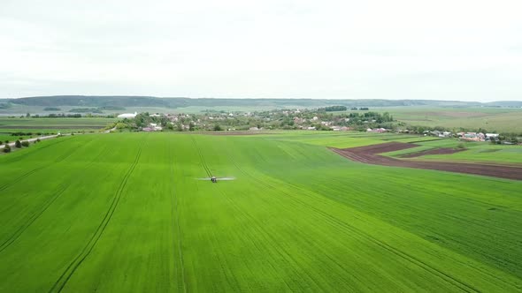 Aerial View of Farming Tractor Spraying on Field with Sprayer Herbicides and Pesticides